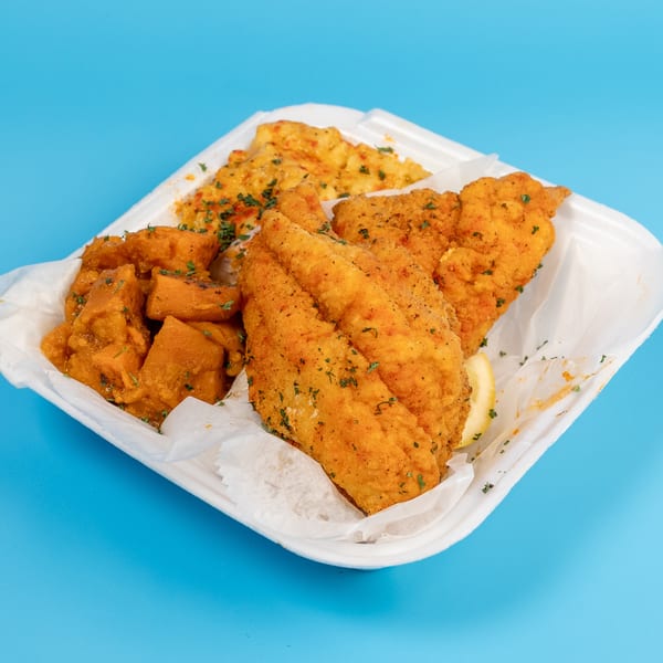 Fried fish fillets, sweet potatoes, and rice in a white takeout container on a blue background.